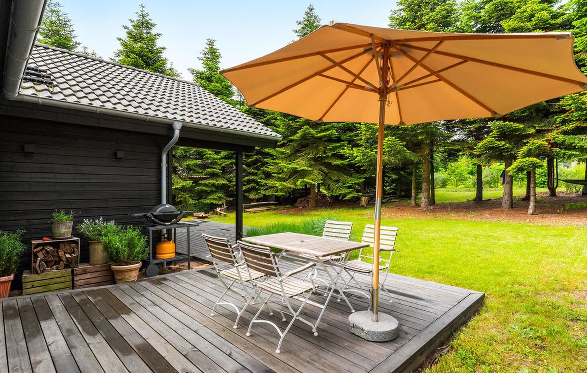 A wooden deck with outdoor furniture and a large umbrella.