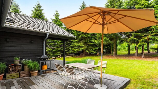 Une terrasse en bois avec des meubles d’extérieur et un grand parasol.