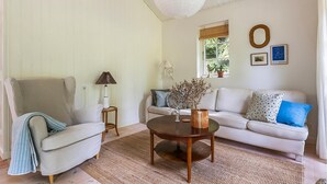 Un salon comprenant un canapé, un fauteuil, une table basse ronde et une lampe.