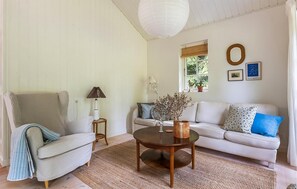 Ein Wohnzimmer mit Sofa, Sessel, rundem Couchtisch und einer Lampe.