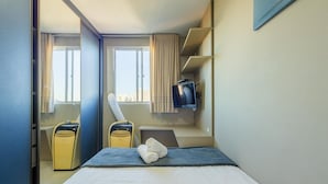 A hotel room with a bed, a TV, a suitcase, and a vacuum cleaner. - Apt With Ocean View in Cond With Pool Ori1001 (Picarras)