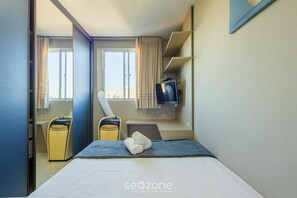 A hotel room with a bed, a TV, a suitcase, and a vacuum cleaner. - Apt With Ocean View in Cond With Pool Ori1001 (Picarras)