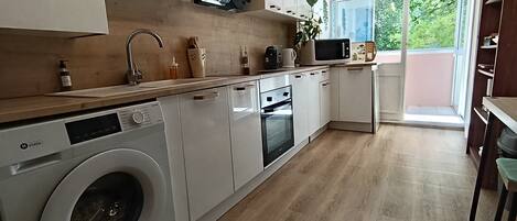 A modern kitchen with a washing machine, microwave, and oven.