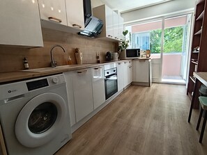 A modern kitchen with a washing machine, microwave, and oven. - Perfect 3-bedroom apartment in Saint-Herblain for your getaway (Saint-Herblain)
