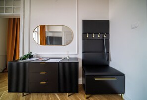 A black vanity with a mirror, a small table with a plant, and a black chair with hooks. - Romantic City Light Loft with Premium Comforts & Central Location – 513 (Budapest)