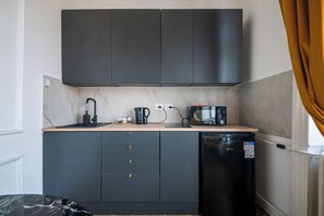 A compact kitchenette with a sink, a coffee maker, a toaster, and a compact refrigerator. - Romantic City Light Loft with Premium Comforts & Central Location – 513 (Budapest)