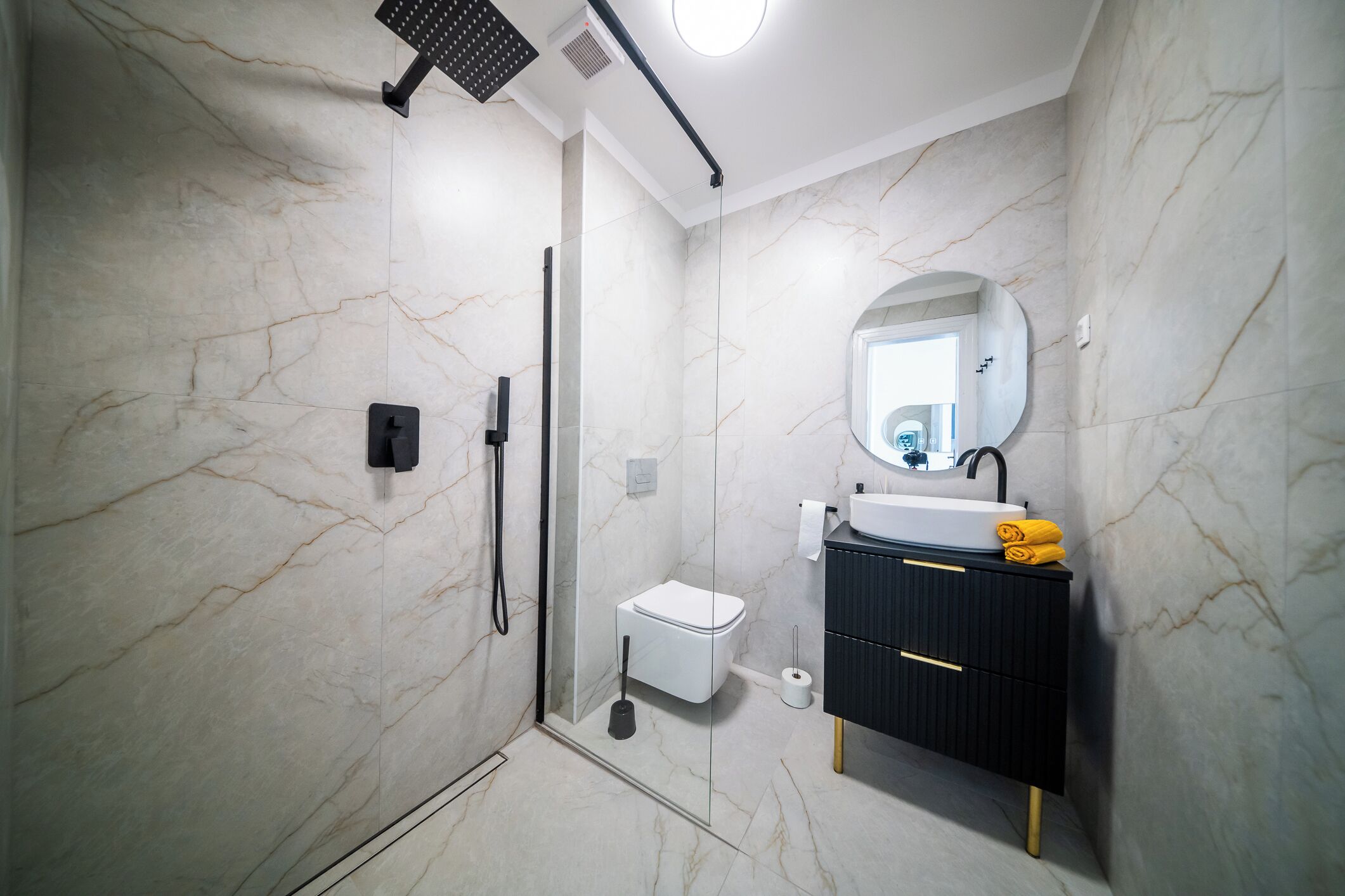 A modern bathroom with a shower, toilet, and vanity.