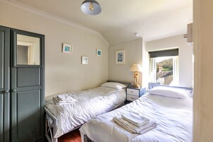 A hotel room with two beds, a nightstand with a lamp, a window with a view, and a door with a mirror.