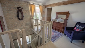Une pièce avec un escalier en bois, une commode en bois, un canapé bleu et un tapis à motifs.
