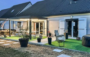 A house with a covered patio area, outdoor seating, and a well-maintained lawn. - Maison Familiale en Campagne (Levis)