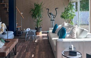 A modern living room with a sofa, a dining table, and two potted plants. - Maison Familiale en Campagne (Levis)