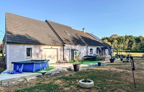 A two-story house with a tiled roof, a garage, and a covered patio area with outdoor furniture. - Maison Familiale en Campagne (Levis)
