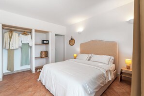 Een slaapkamer met een bed, een kledingkast en een nachtkastje.