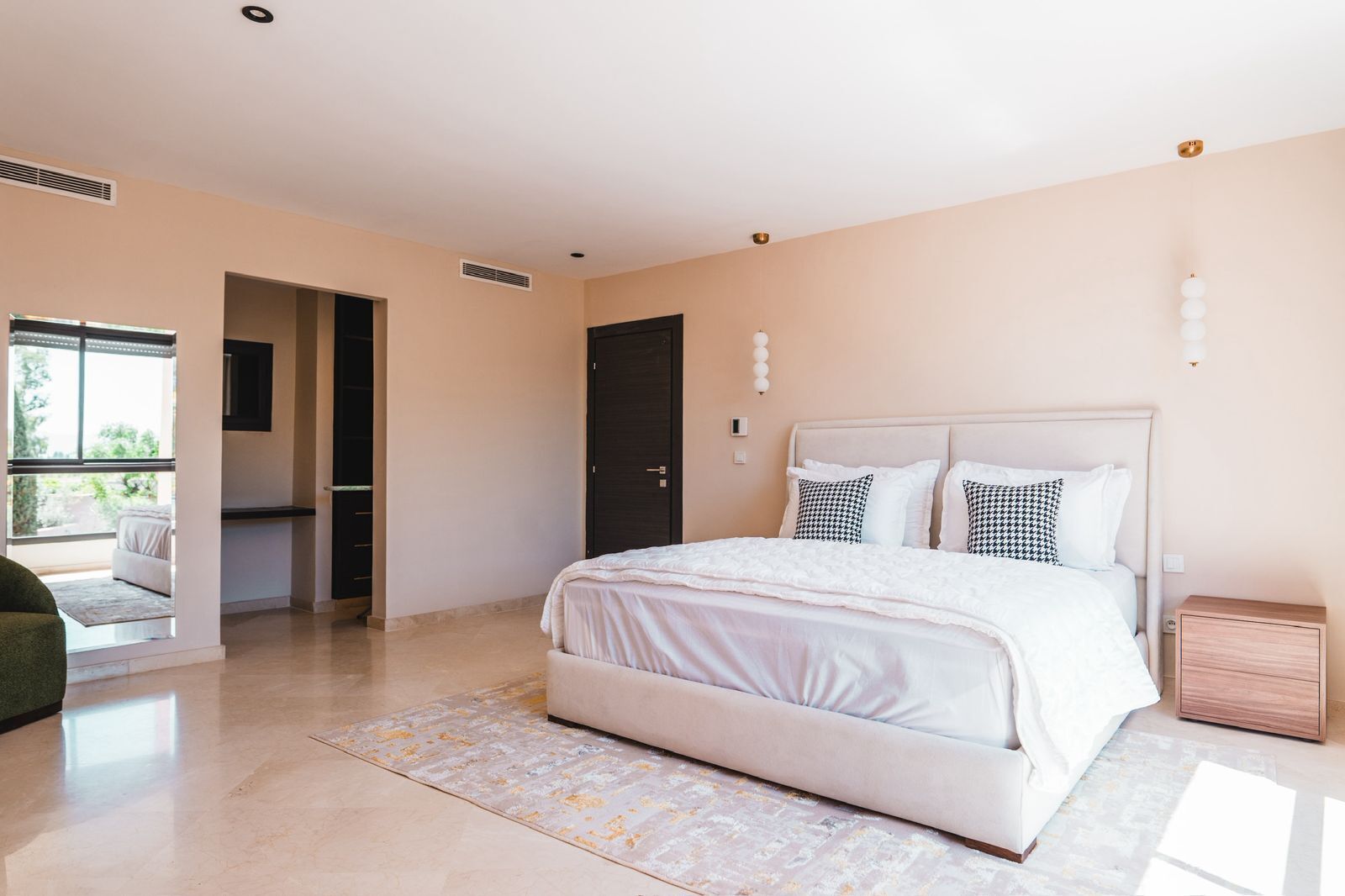 A bedroom with a bed, bedside tables, a window, and a door leading to another room.