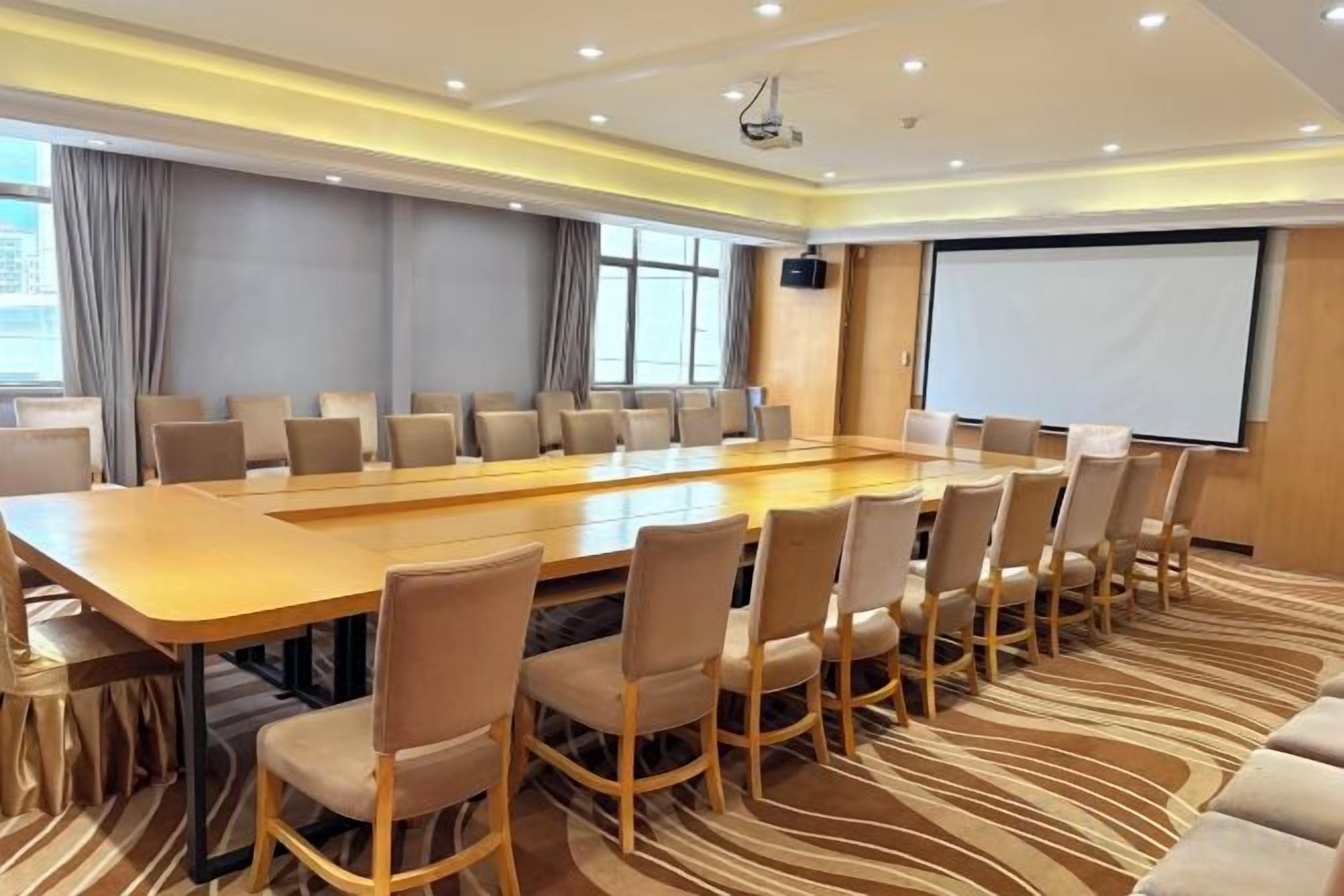 A conference room with a long table and chairs, a projector screen, and a large window.