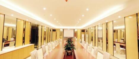 A conference room with a long table, chairs, and a potted plant.