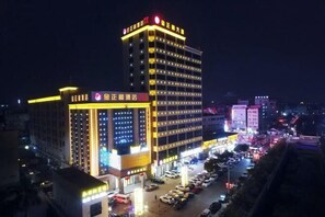 Un hôtel à plusieurs étages, doté d’une enseigne lumineuse et d’un parking.