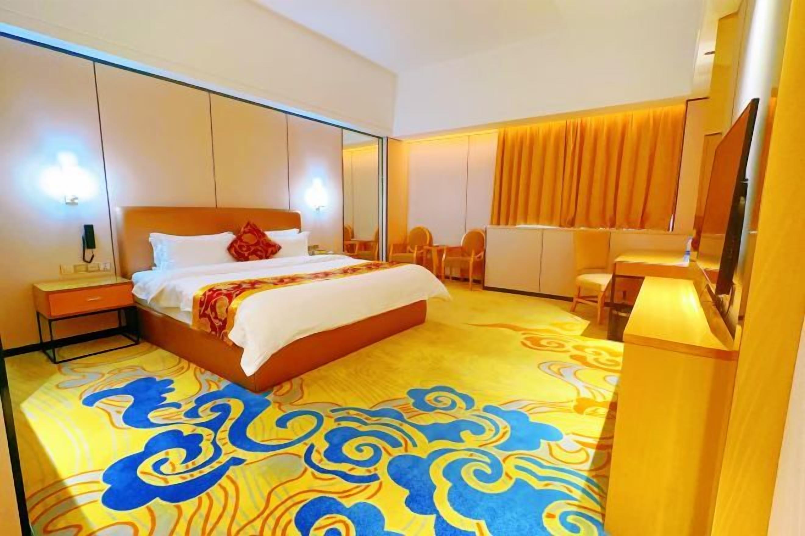 Une chambre d’hôtel avec un grand lit, une table de chevet et un bureau avec une chaise.