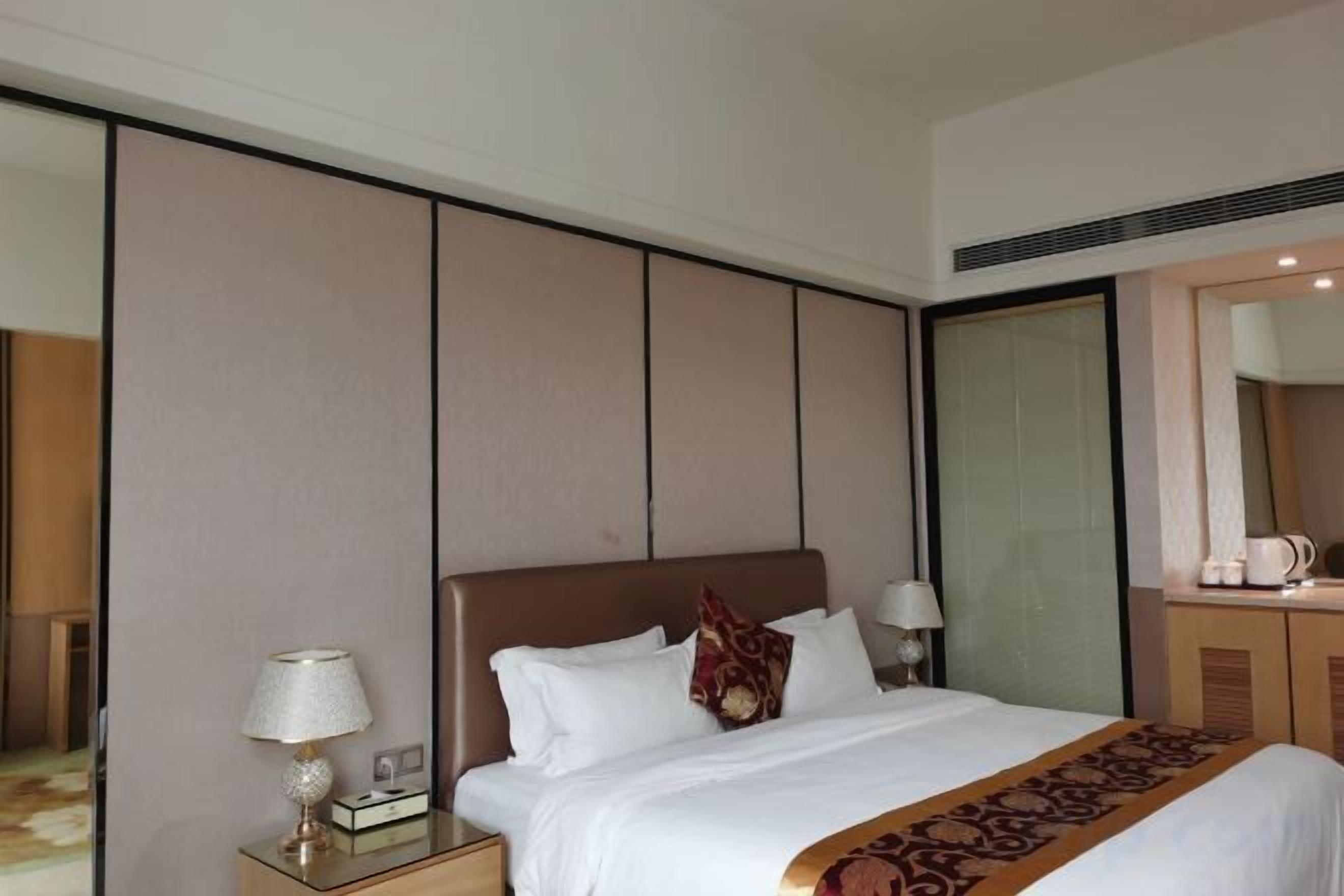 Una camera d'albergo con un letto grande, comodini, uno specchio e un armadio.