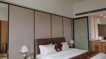 A hotel room with a large bed, bedside tables, a mirror, and a wardrobe.