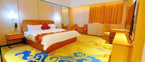 A hotel room with a bed, bedside table, and a desk with a chair.