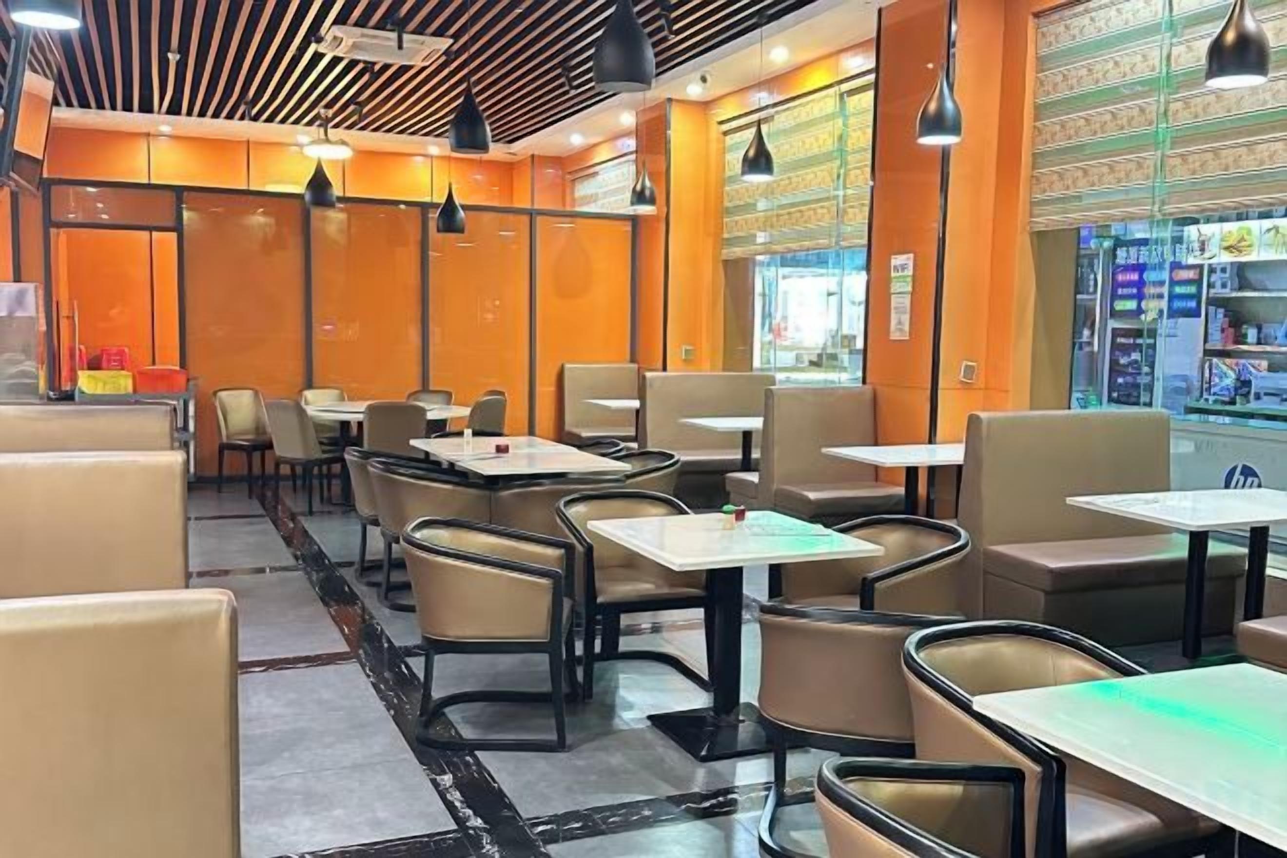 A restaurant interior with booths and tables, a patterned floor, and pendant lighting.