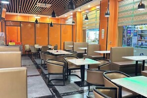 A restaurant interior with booths and tables, a patterned floor, and pendant lighting. - Dongguan Jinzhenghe Hotel (Dongguan)