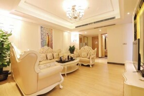 Un salon spacieux avec un plafond haut, un lustre et un grand tableau accroché au mur.