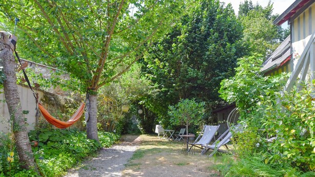 Un jardín con una hamaca, mobiliario exterior y un camino de grava.
