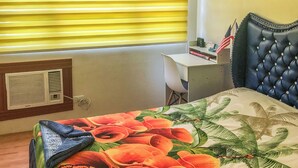 A bedroom with a bed, a desk, and a window with blinds. - Seawind Condominium (Davao City)