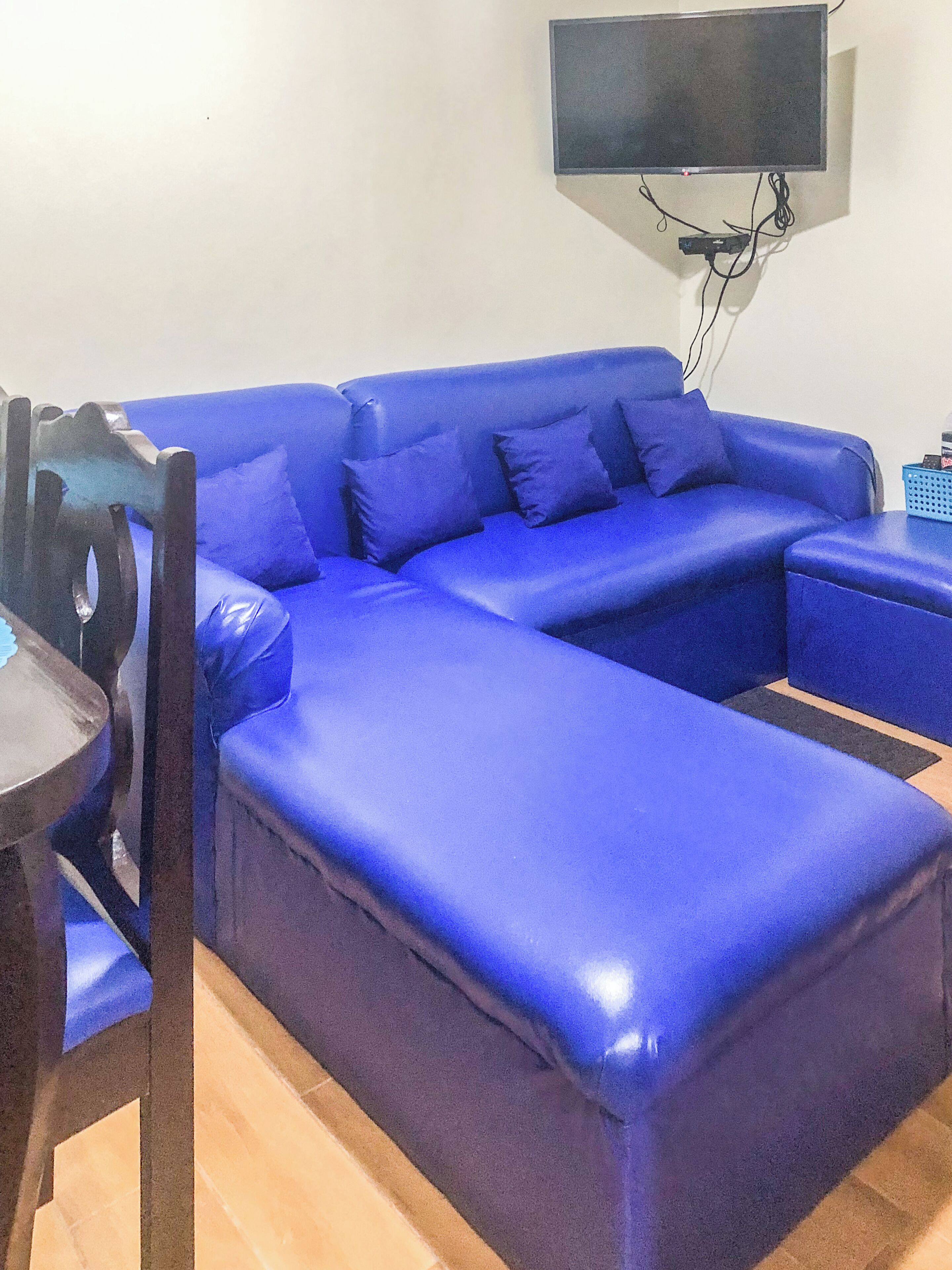 A blue sofa with a flat-screen TV mounted on the wall above it.