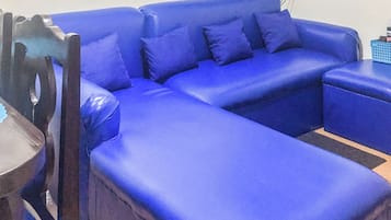 A blue sofa with a flat-screen TV mounted on the wall above it.