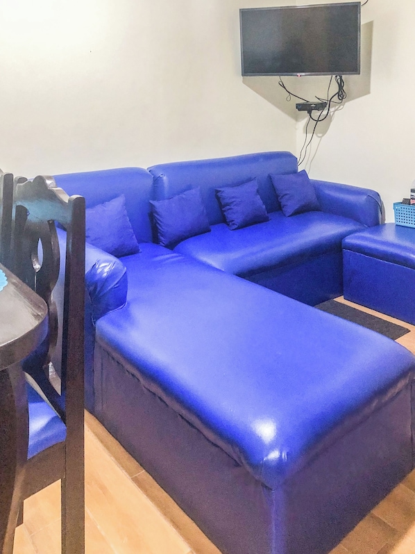 A blue sofa with a flat-screen TV mounted on the wall above it. - Seawind Condominium (Davao City)