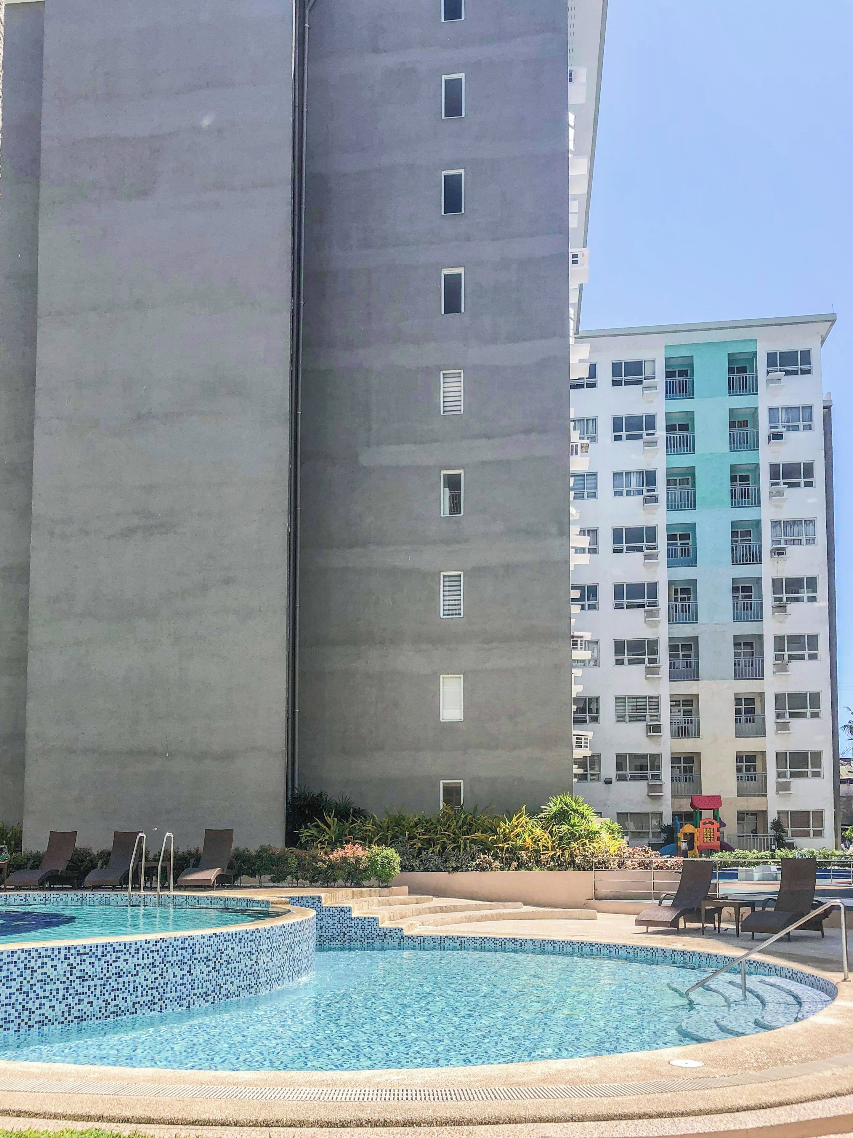 Un hotel con area piscina, inclusi lettini e un'area giochi per bambini.