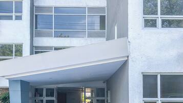 A modern building with a flat facade, large windows, and a covered entrance area.