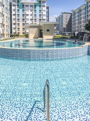 A swimming pool with a tiled edge, surrounded by multi-story residential buildings. - Seawind Condominium (Davao City)