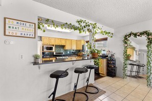 A modern kitchen with wooden cabinets, a black countertop, and a bar area with stools. - Fun-Filled, Pet-Friendly 4BR Home w/ Private Halfpipe, Small Pool & Hot Tube! (Las Vegas)