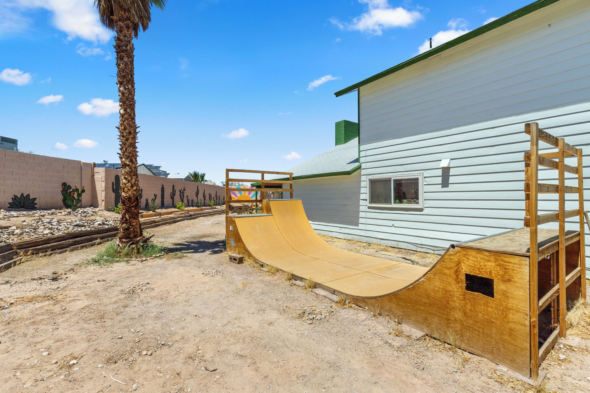 A residential area with a wooden ramp leading to a house with white siding.