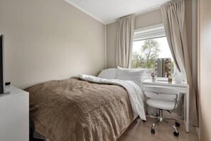 A bedroom with a bed, a desk with a chair, a window with curtains, and a mirror with lights. - Exclusive South Tromsøya home peaceful & central (Tromsø)