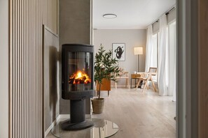 A modern living room with a wood-burning stove, a potted plant, and a dining area with a table and chairs. - Exclusive South Tromsøya home peaceful & central (Tromsø)
