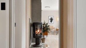 A hallway with a central fireplace, wooden flooring, and a door on the right. - Sydpol Designer Home Northern Lights View (Tromsø)