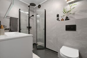 A modern bathroom with a glass-enclosed shower, a white sink, and a toilet. - Exclusive South Tromsøya home peaceful & central (Tromsø)