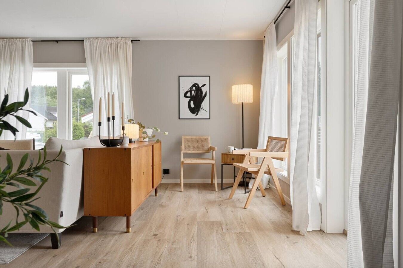 A room with a wooden desk, two chairs, a lamp, and a framed artwork on the wall.
