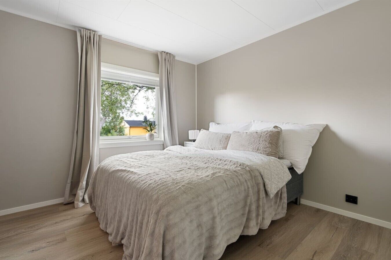 Une chambre à coucher avec un lit, des rideaux, une fenêtre et une table de chevet.
