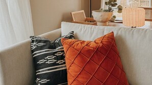 A living room with a sofa, cushions, a floor lamp, a framed artwork, and a view through a window. - Sydpol Designer Home Northern Lights View (Tromsø)