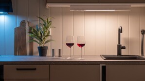 A kitchen with a countertop, two wine glasses, a potted plant, and a sink. - Sydpol Designer Home Deluxe Apartment (Tromsø)