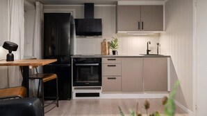 A compact kitchen with a built-in oven, a black range hood, and a small countertop. - Sydpol Designer Home Deluxe Apartment (Tromsø)