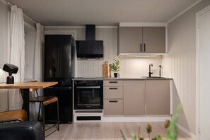 A compact kitchen with a built-in oven, a black range hood, and a small countertop. - Sydpol Designer Home Deluxe Apartment (Tromsø)