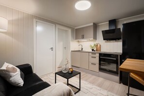A compact living space with a kitchenette, a sofa, a coffee table, and a TV. - Sydpol Designer Home Classic Apartment (Tromsø)