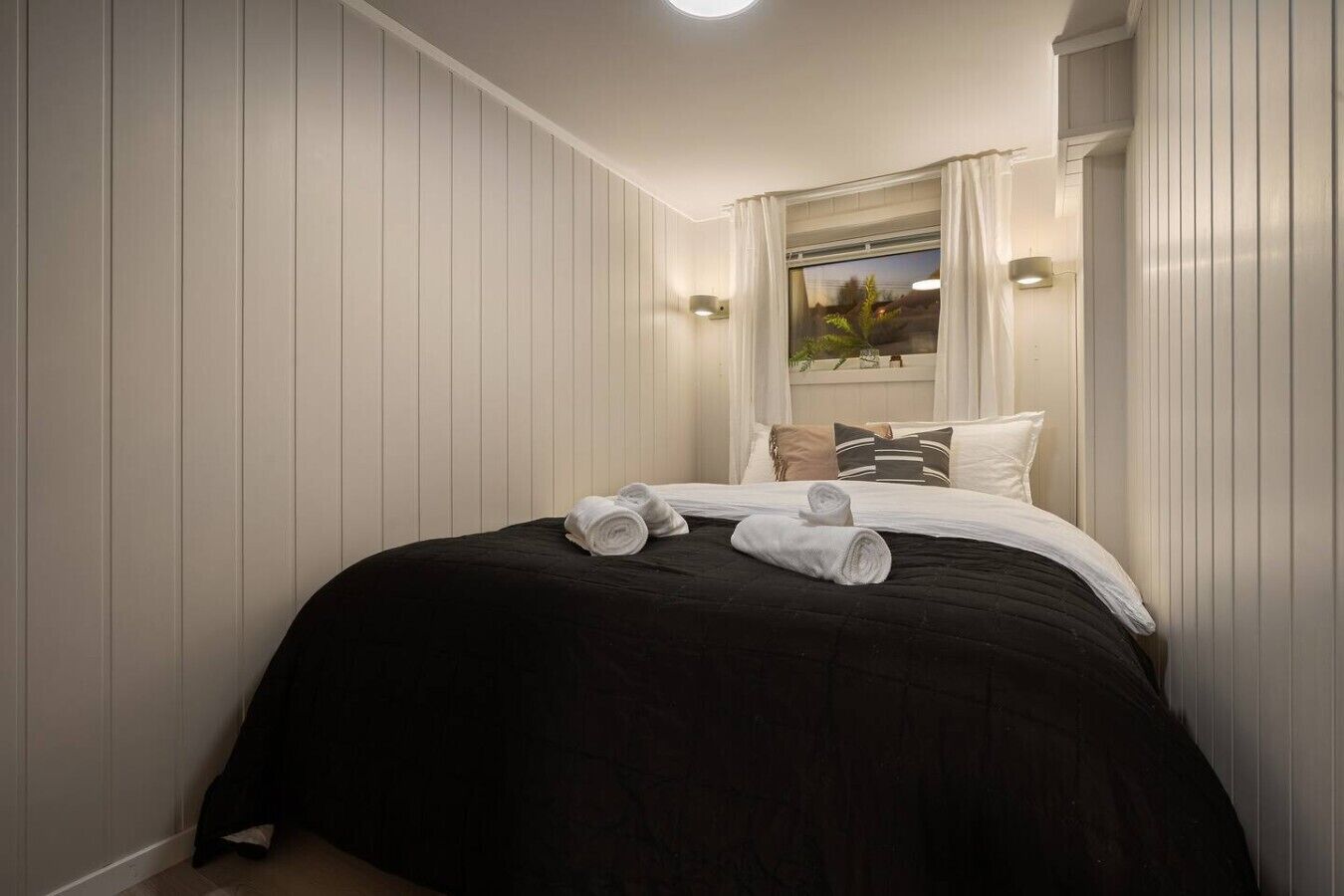 Ein Hotelzimmer mit Bett, Kissen und einem fensterbepflanzten Fenster.